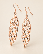 The Sova CZ Drop Earrings — Warm gold-color openwork leaf drop pair in a front three-quarter studio view on pale greige; reference-based AI visualization