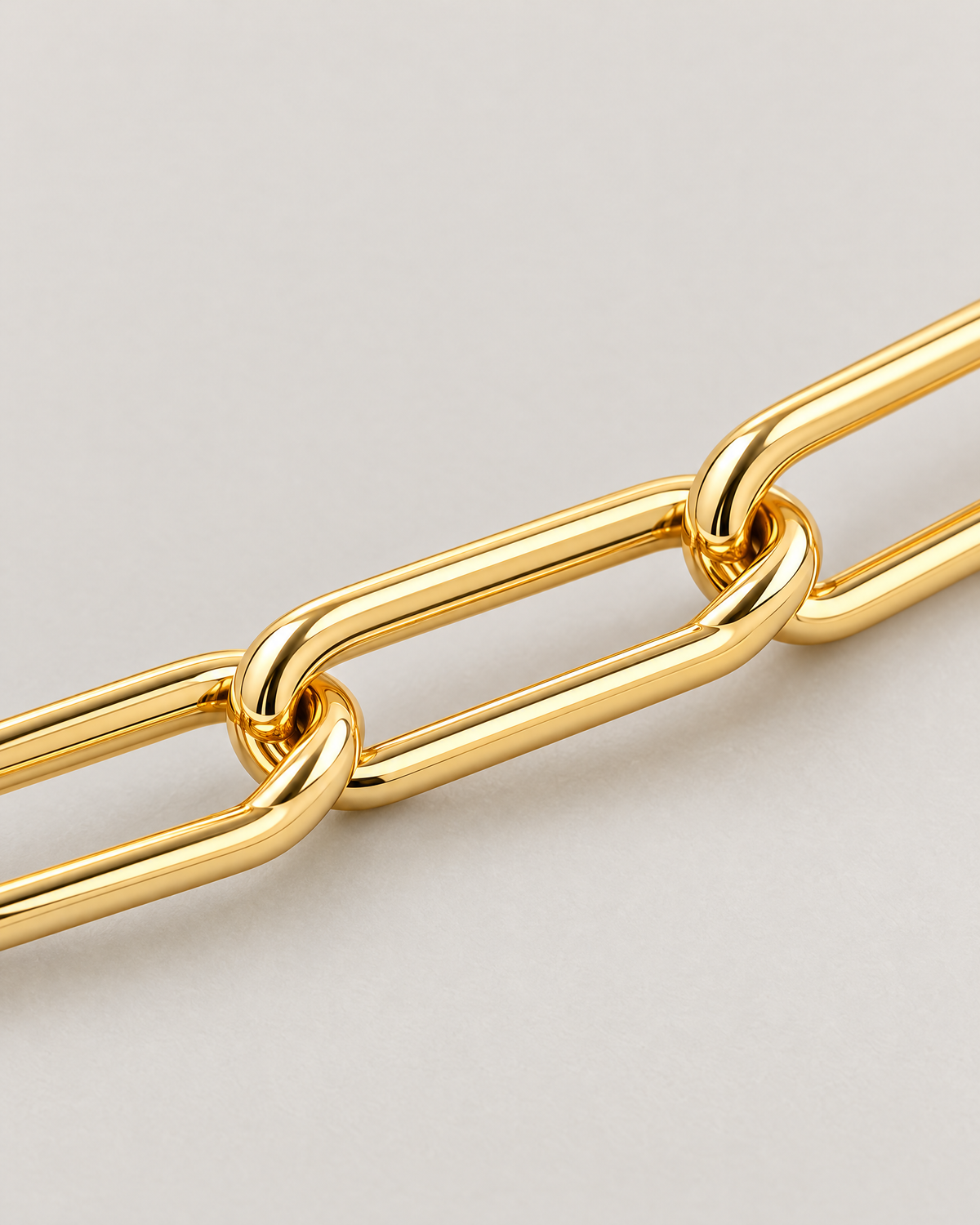 The Linnea Link Bracelet — polished gold-color interlocked paperclip-link macro on pale greige — reference-based AI visualization