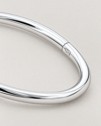 The Talo Open Cuff Bangle — polished silver-tone closed bangle latch and seam detail on pale greige; reference-based AI visualization