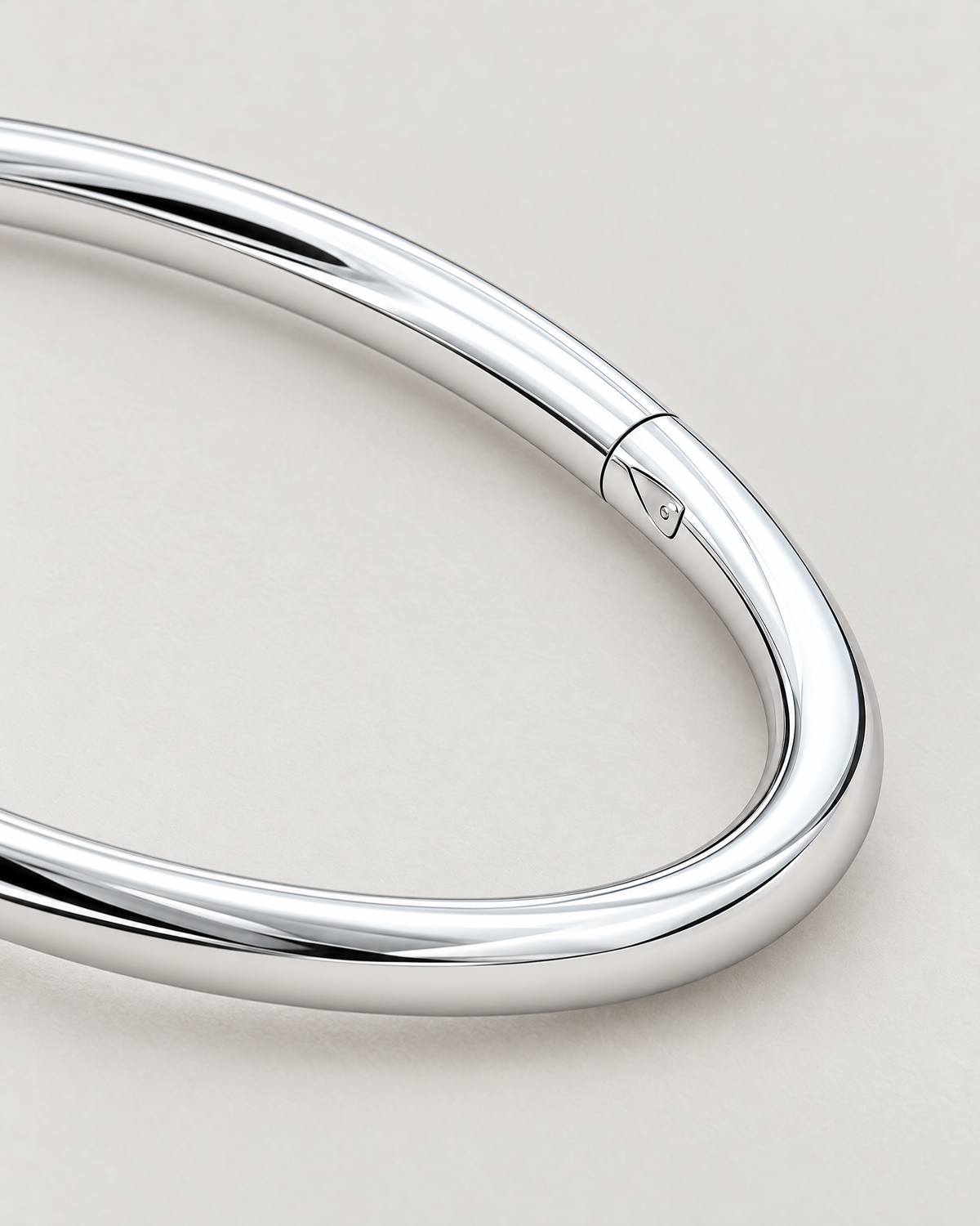 The Talo Open Cuff Bangle — polished silver-tone closed bangle latch and seam detail on pale greige; reference-based AI visualization
