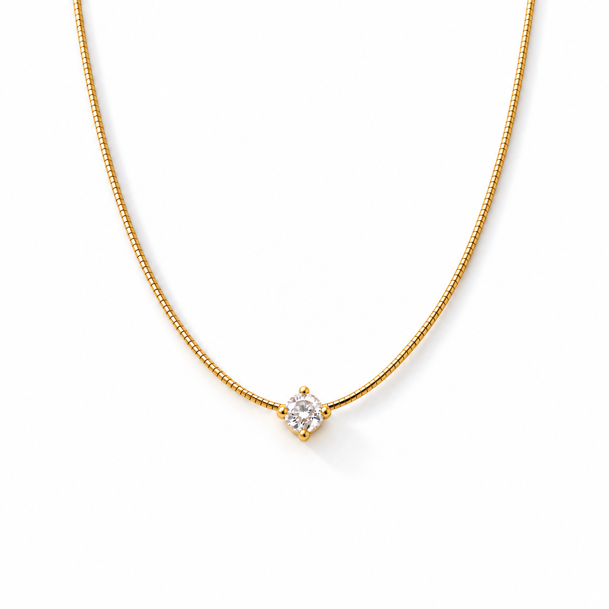 Gold-color necklace detail showing the clear round four-prong stone, segmented chain, lobster clasp, extension links, and smooth end tag on pale warm greige; reference-based AI visualization.
