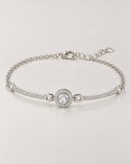 The Sora Halo Bracelet polished cool silver-tone complete shallow-oval hero with clear-stone halo, curved stone-set bars, fine chain and open-link extension on pale greige reference-based AI visualization