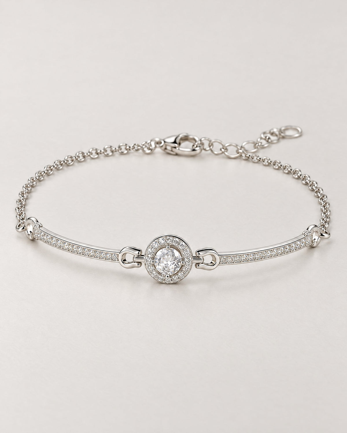 The Sora Halo Bracelet polished cool silver-tone complete shallow-oval hero with clear-stone halo, curved stone-set bars, fine chain and open-link extension on pale greige reference-based AI visualization