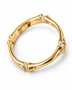 The Ebba Bamboo Band in polished yellow-gold color with clear round stone accents, close elevated three-quarter product-only studio view on a pearl-white background; reference-based AI visualization.