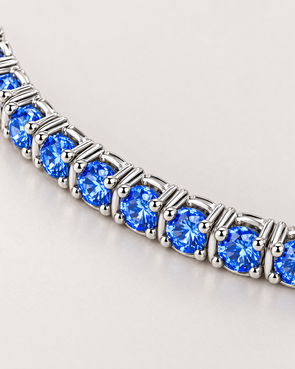 The Orla CZ Tennis Bracelet — blue round-stone and silver-tone articulated setting macro on pale greige — reference-based AI visualization