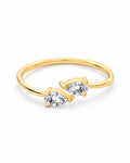 The Agnes Twin-Pear Ring in a polished yellow-gold finish with two clear pear-shaped stones, whole-ring front three-quarter product-only view on a pearl-white studio background — reference-based AI visualization