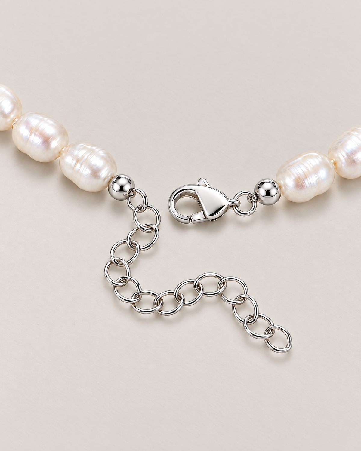 Close view of irregular off-white pearls, a silver-tone clasp and oval-link extension on a pale greige studio surface; reference-based AI visualization