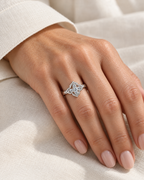 The Seren Quatrefoil Moissanite Ring in visible silver-tone finish, elegant on-hand view on a light-warm-skinned adult hand with ivory linen, reference-based AI visualization.