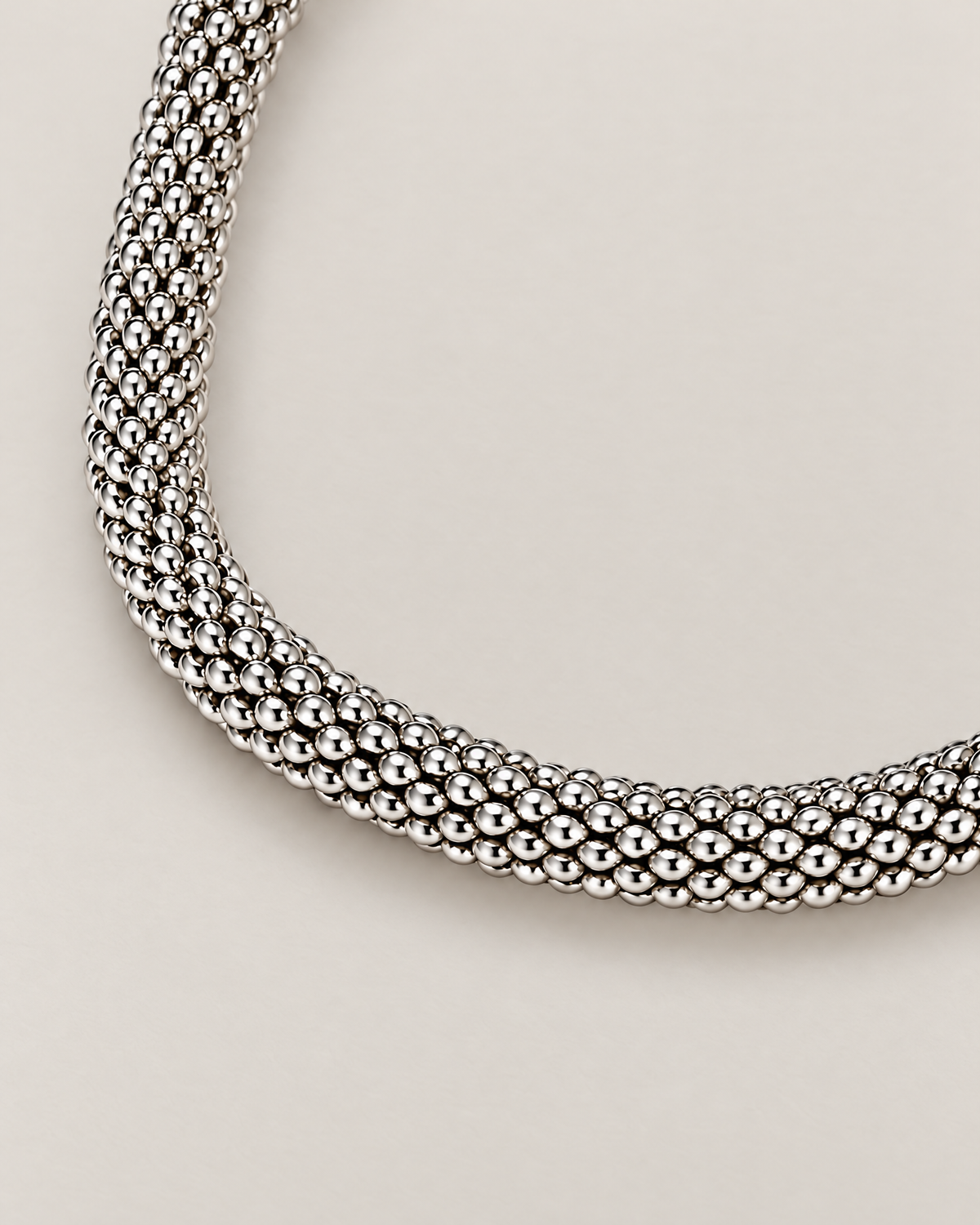 The Liva Mesh Chain Bracelet silver-tone woven mesh in a curved macro composition on warm pale greige; reference-based AI visualization.