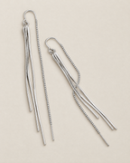The Neri Threader Earrings, paired bright silver-tone vertical and diagonal tassel threaders on pale greige, reference-based AI visualization