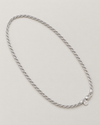 The Gala Twisted Rope Chain Necklace in polished silver, complete diagonal oval lay on pale greige, reference-based AI visualization