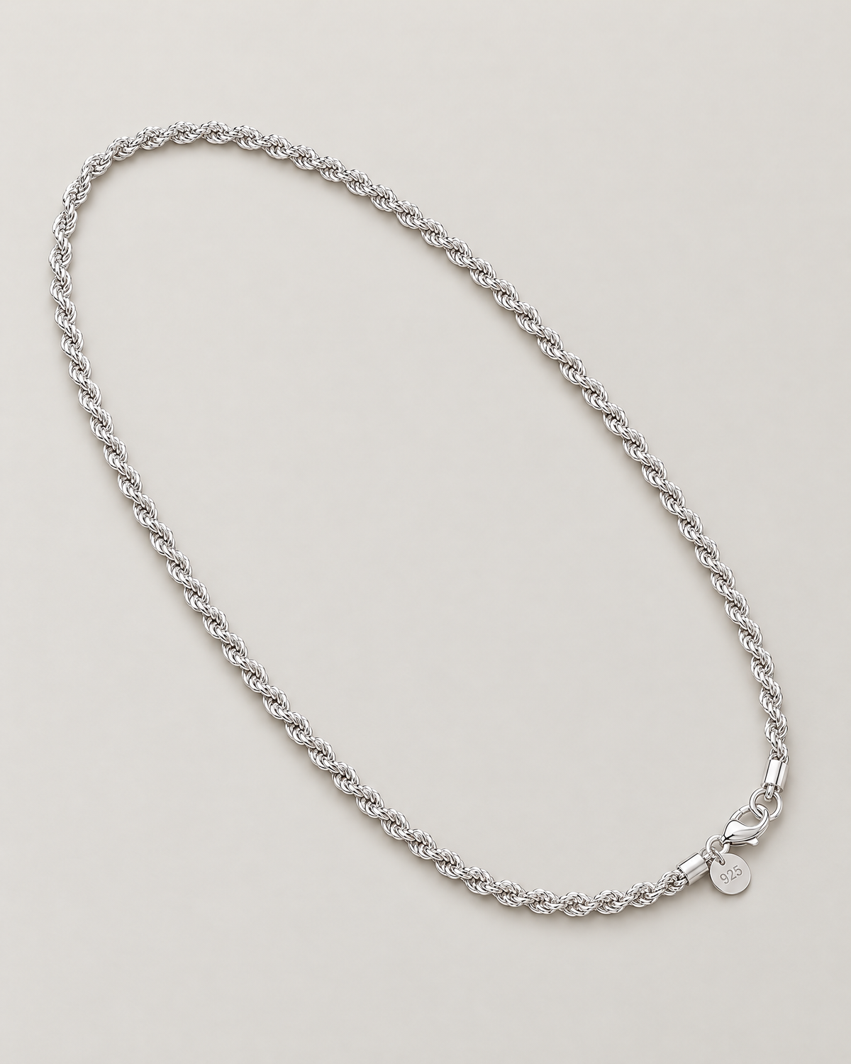 The Gala Twisted Rope Chain Necklace in polished silver, complete diagonal oval lay on pale greige, reference-based AI visualization
