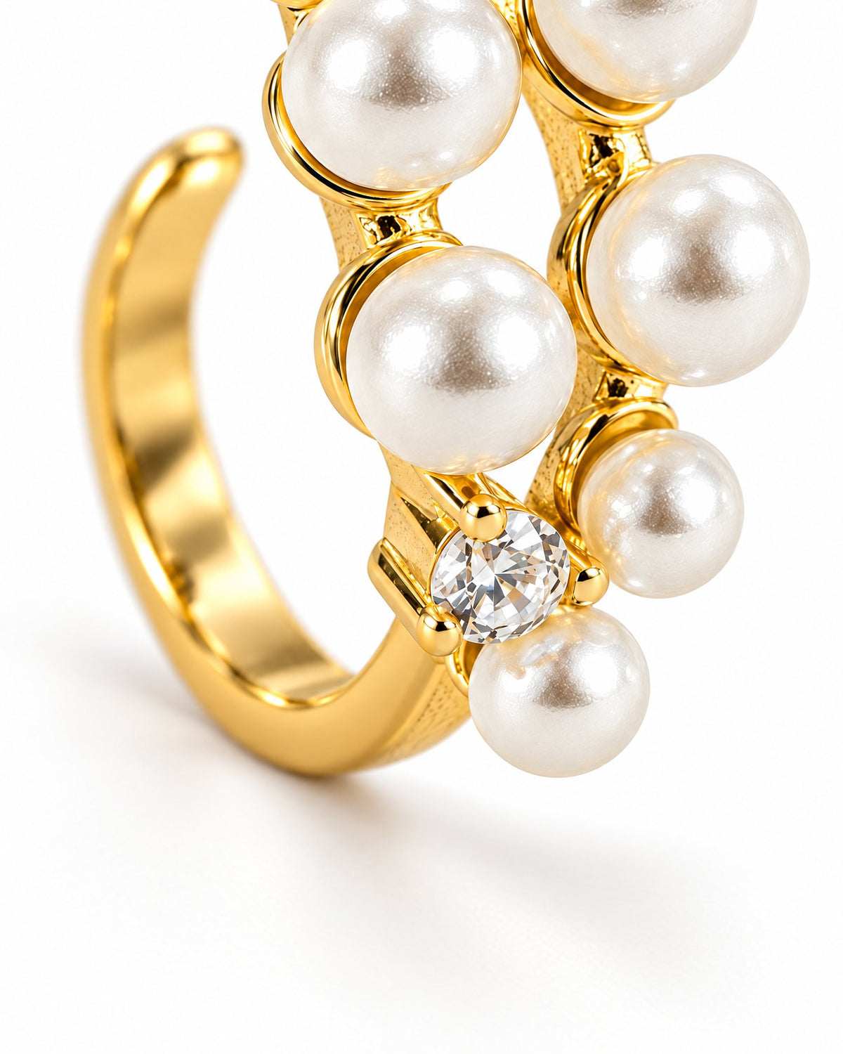 The Ilse Pearl Cluster Ring in observed gold finish, lower-setting macro view of a clear round faceted accent, petite gold prongs, pearl-like cabochons, and the open-band curve on a pearl-white background; reference-based AI visualization.