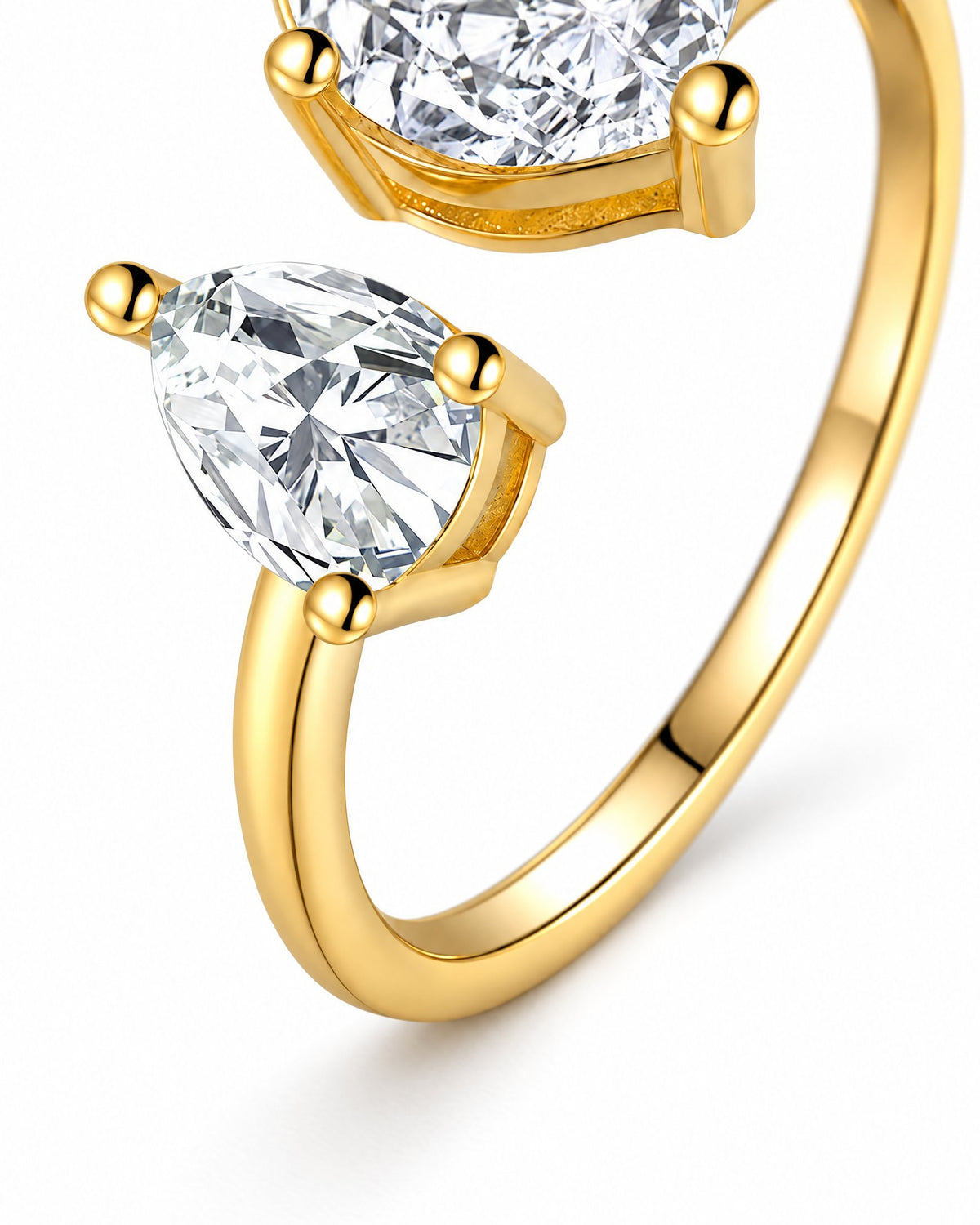 Macro detail of The Nessa Heart & Pear Ring in polished yellow-gold-tone metal with clear faceted heart and pear stones on a pearl-white studio background — reference-based AI visualization.