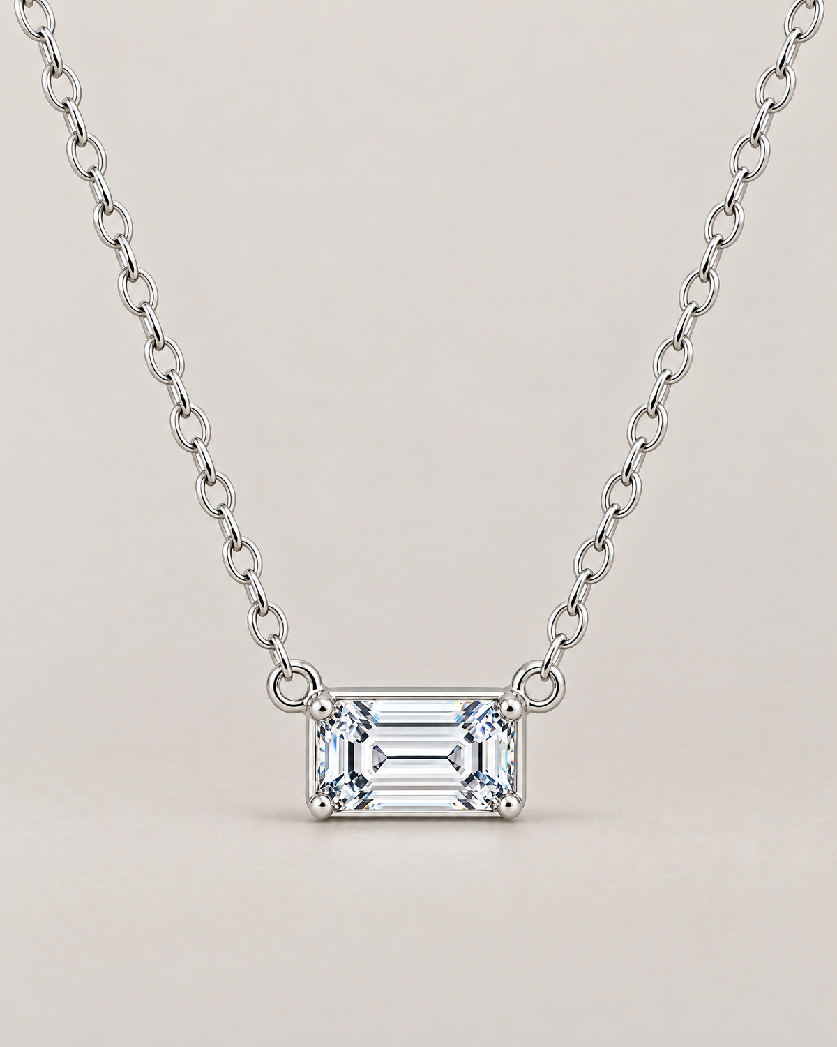 The Mara Geometric CZ Pendant — jewelry-only straight-on hero with a horizontal clear rectangular stone, four corner prongs, side connector rings, and an alternating-link chain on pale warm greige; reference-based AI visualization