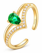 The Tuva Green Pear Wrap Ring in an oblique polished gold-color setting view with a green pear-shaped stone and clear round accents on a pearl-white studio background, reference-based AI visualization