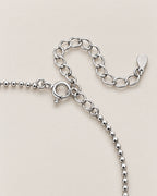 The Eden Moissanite Bracelet silver-tone spring-ring clasp, ball-bead chain, and oval-link extension detail on a pale-greige background, reference-based AI visualization.
