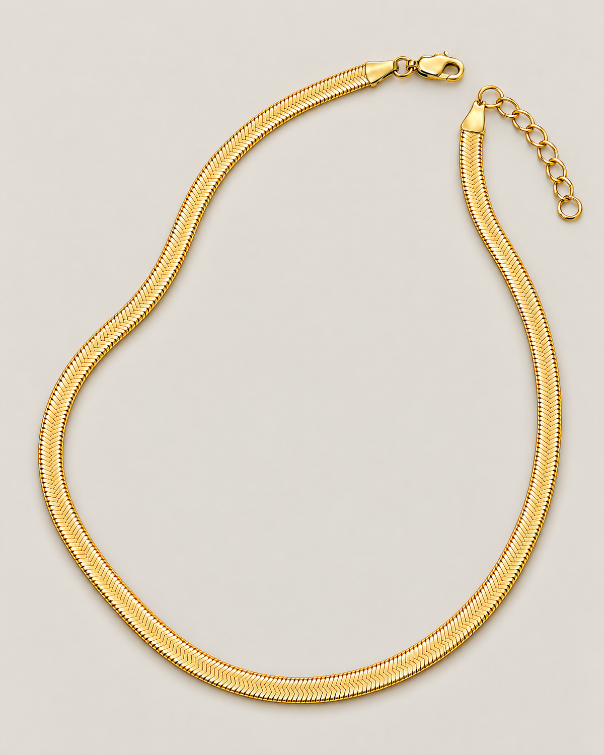 Gold-tone flat herringbone necklace in an asymmetrical open loop with the clasp and oval-link extender separated at the top on a pale greige studio ground; reference-based AI visualization