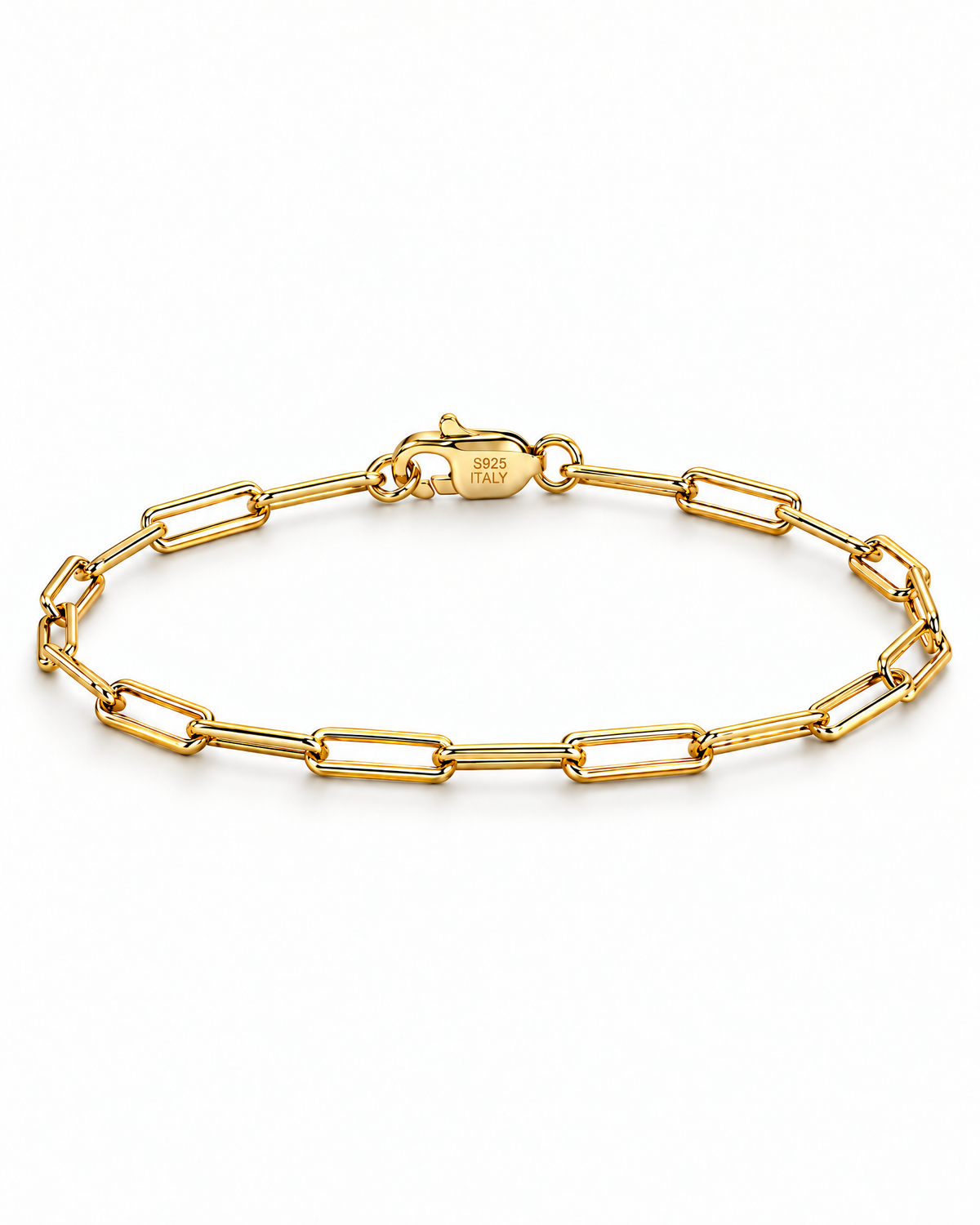 The Aelin Paperclip Bracelet in polished yellow-gold tone, shown as a full closed oval with the marked clasp at the top on a plain pearl-white studio surface; reference-based AI visualization