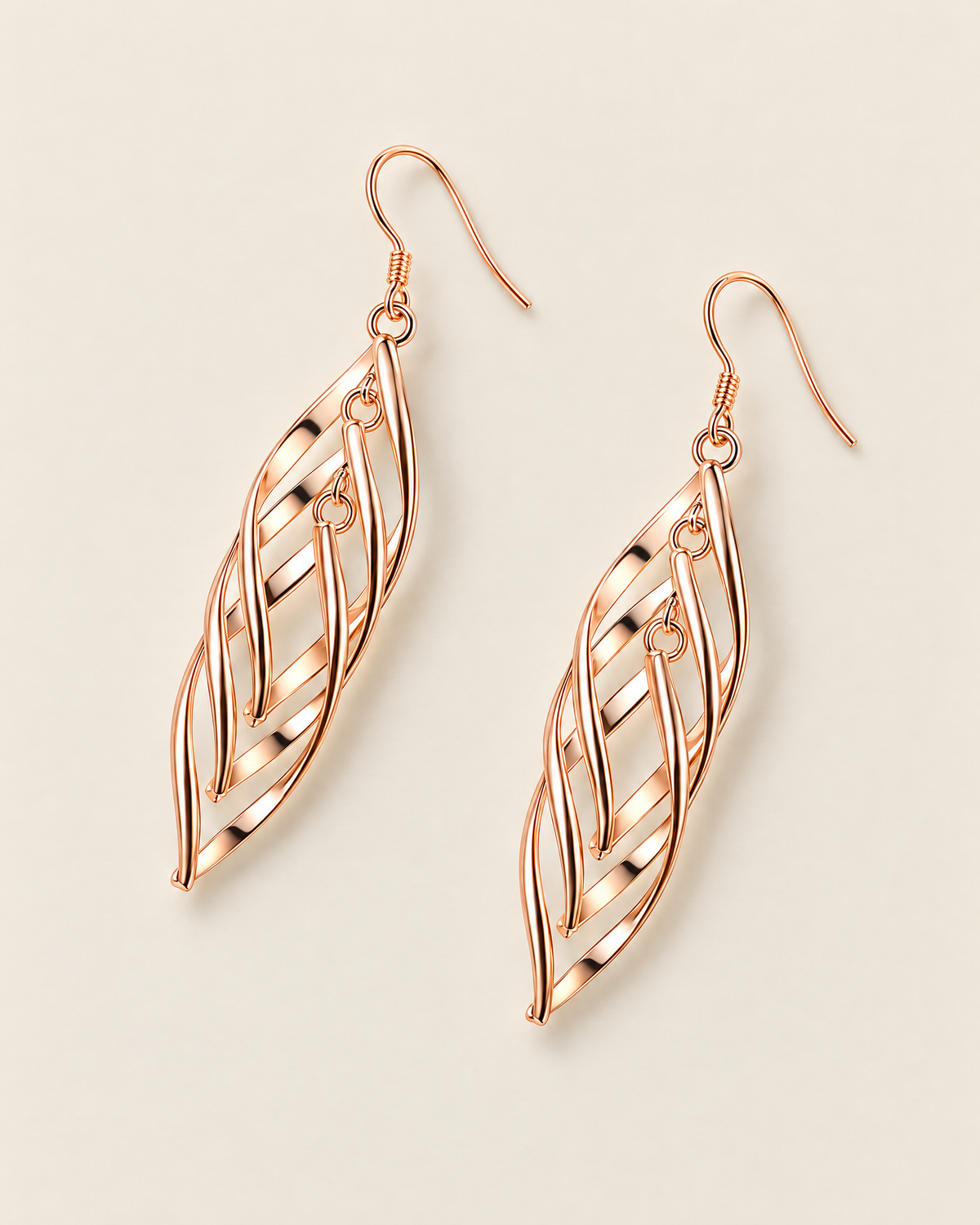 The Sova CZ Drop Earrings — Warm gold-color openwork leaf drop pair in a separated mirrored flat lay on pale greige; reference-based AI visualization