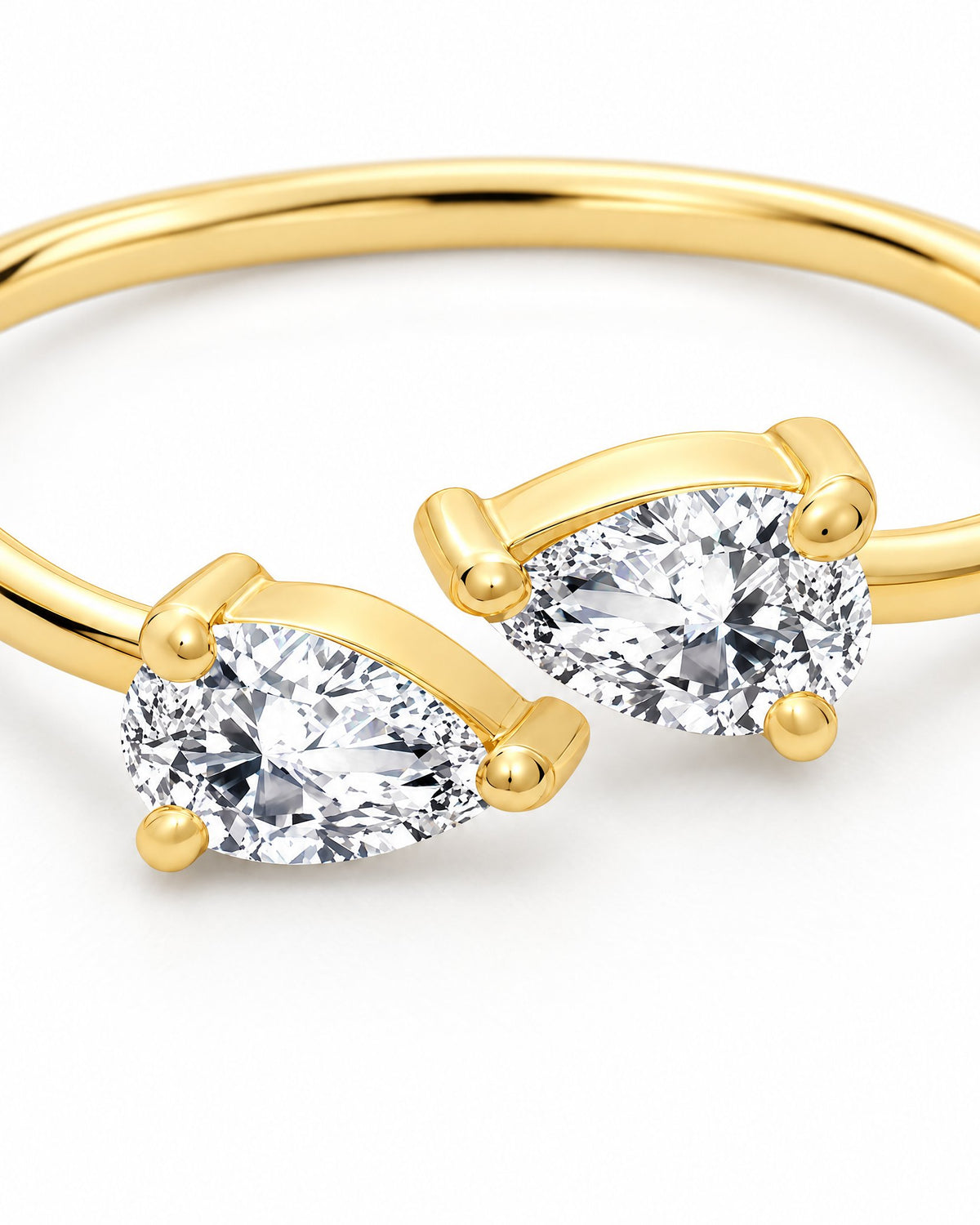 The Agnes Twin-Pear Ring in a polished yellow-gold finish with two clear pear-shaped stones, close twin-pear and prong detail on a pearl-white studio background — reference-based AI visualization