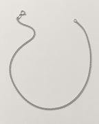The Erin Fine Curb Chain Necklace — Sterling Silver complete relaxed flowing open-U curb-chain lay with spring-ring clasp and oval tag on pale greige, reference-based AI visualization.