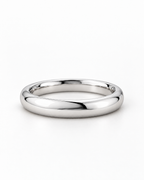The Norden Plain Band Ring in polished silver, low side-profile resting view on a pearl-white studio background, reference-based AI visualization.