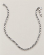 The Gala Twisted Rope Chain Necklace in polished silver, complete relaxed open-U lay on pale greige, reference-based AI visualization