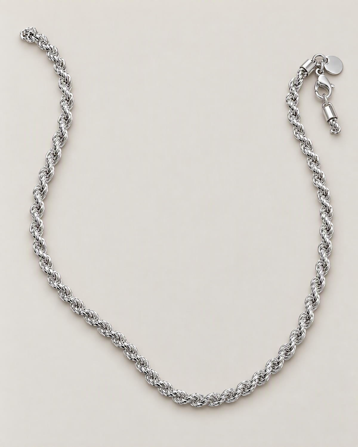 The Gala Twisted Rope Chain Necklace in polished silver, complete relaxed open-U lay on pale greige, reference-based AI visualization