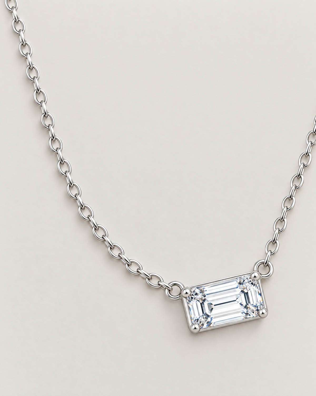 The Mara Geometric CZ Pendant — jewelry-only spacious overhead arrangement with a horizontal clear rectangular stone and alternating-link chain on pale warm greige; reference-based AI visualization