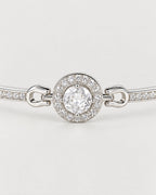 The Sora Halo Bracelet polished cool silver-tone four-prong clear center stone and circular small-clear-stone halo on pale greige reference-based AI visualization