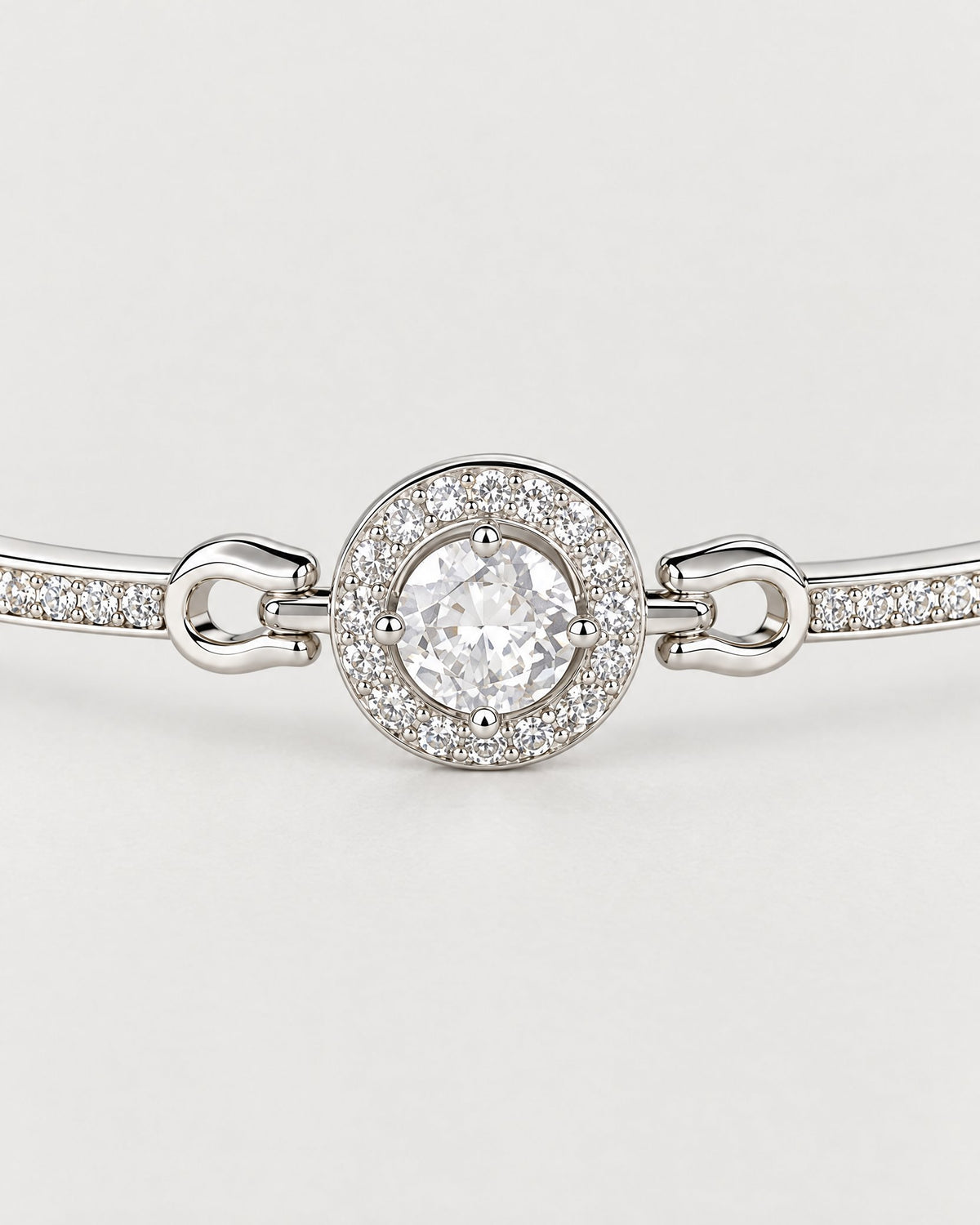 The Sora Halo Bracelet polished cool silver-tone four-prong clear center stone and circular small-clear-stone halo on pale greige reference-based AI visualization