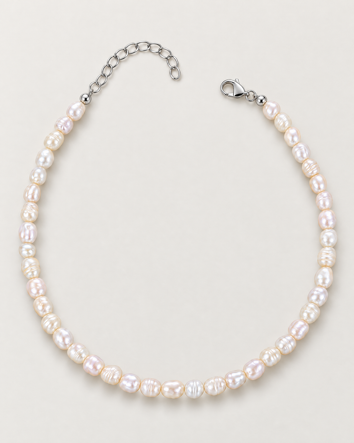 Irregular off-white pearl strand arranged in an open horseshoe with separated clasp and extension ends on a pale greige studio surface; reference-based AI visualization
