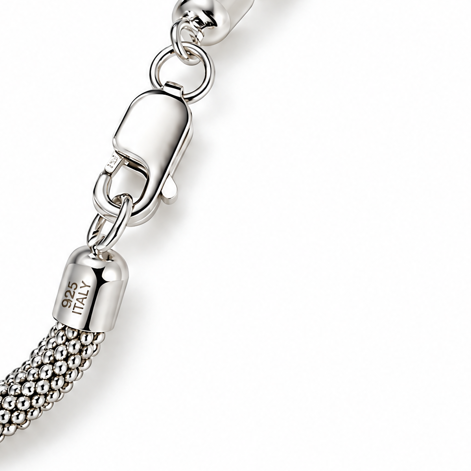The Liva Mesh Chain Bracelet clasp detail in silver-tone metal with woven mesh, oval connector rings, and visible 925 ITALY end-cap marking on warm pale greige; reference-based AI visualization.